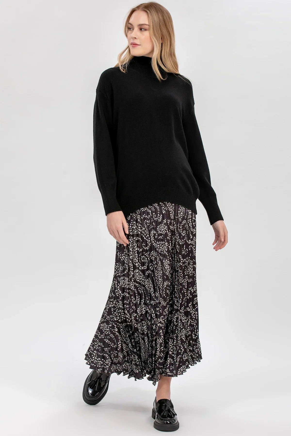 Maglia premaman nera con collo a lupetto di Pietro Brunelli Maternity e gonna a fantasia.