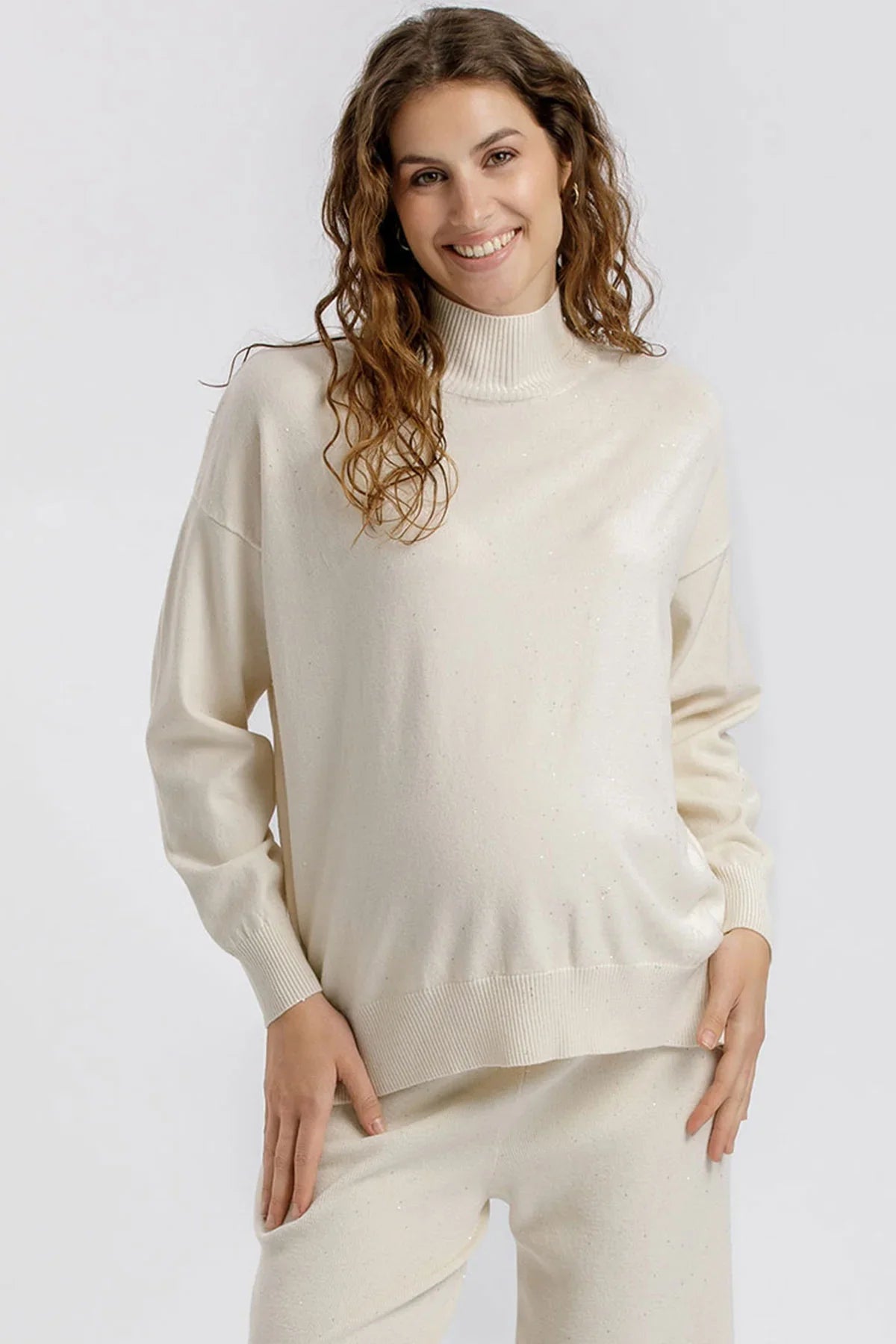 Maglia premaman crema con collo alto e dettagli luminosi. Vestibilità morbida e rilassata. Perfetta prima, durante e dopo la gravidanza
