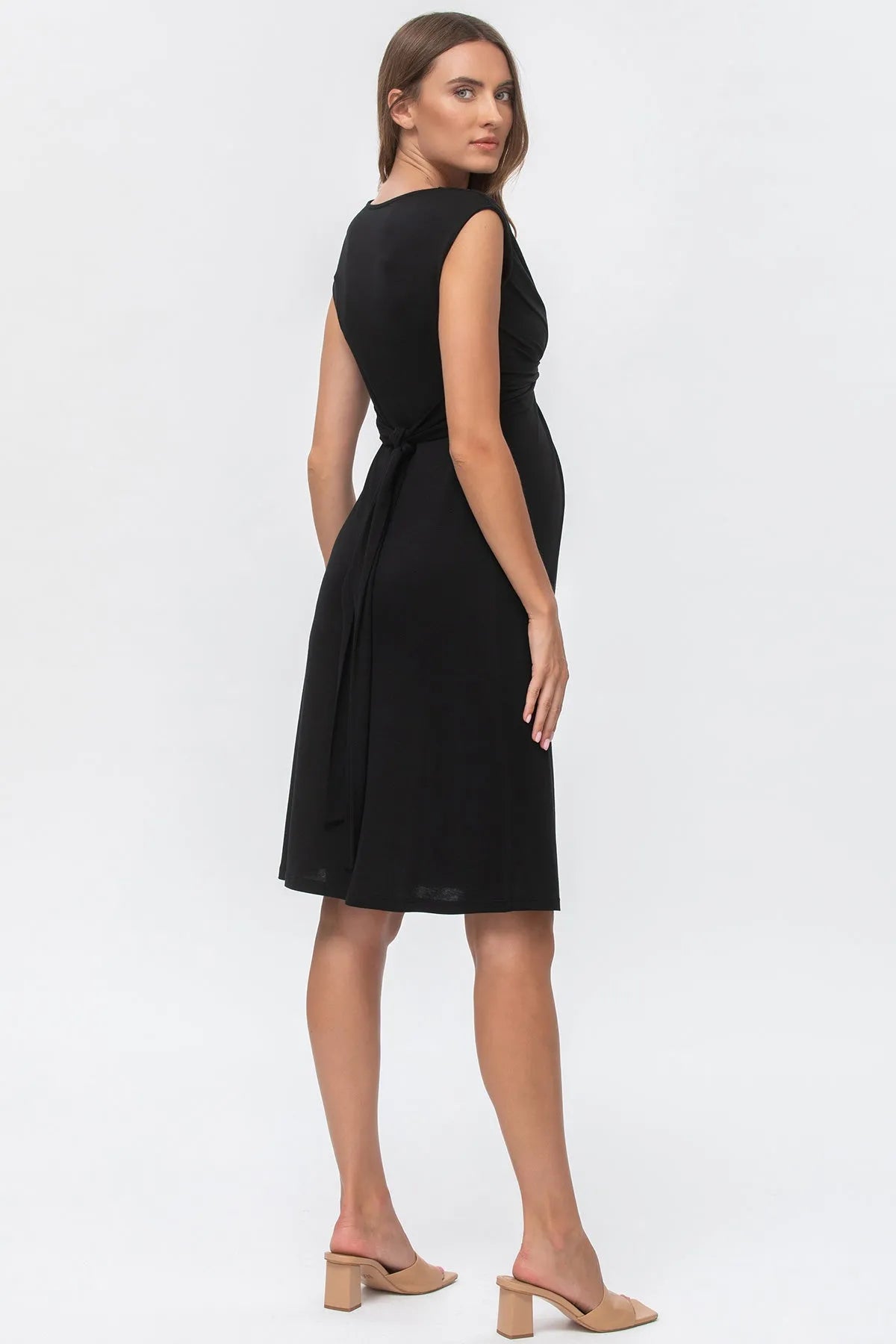 Abito premaman nero elegante senza maniche con cintura, indossato da donna, sfondo bianco.
