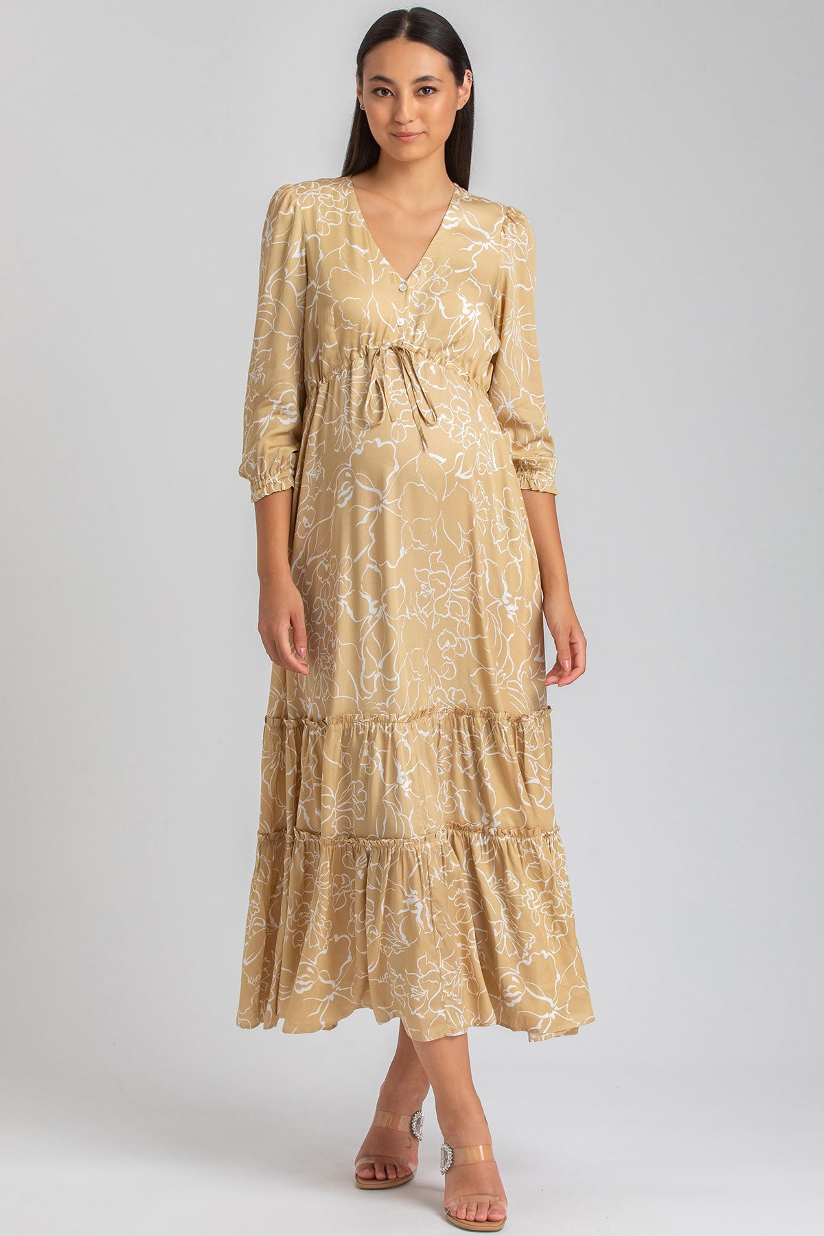 Abito premaman elegante lungo beige con fantasia floreale bianca e maniche a tre quarti.