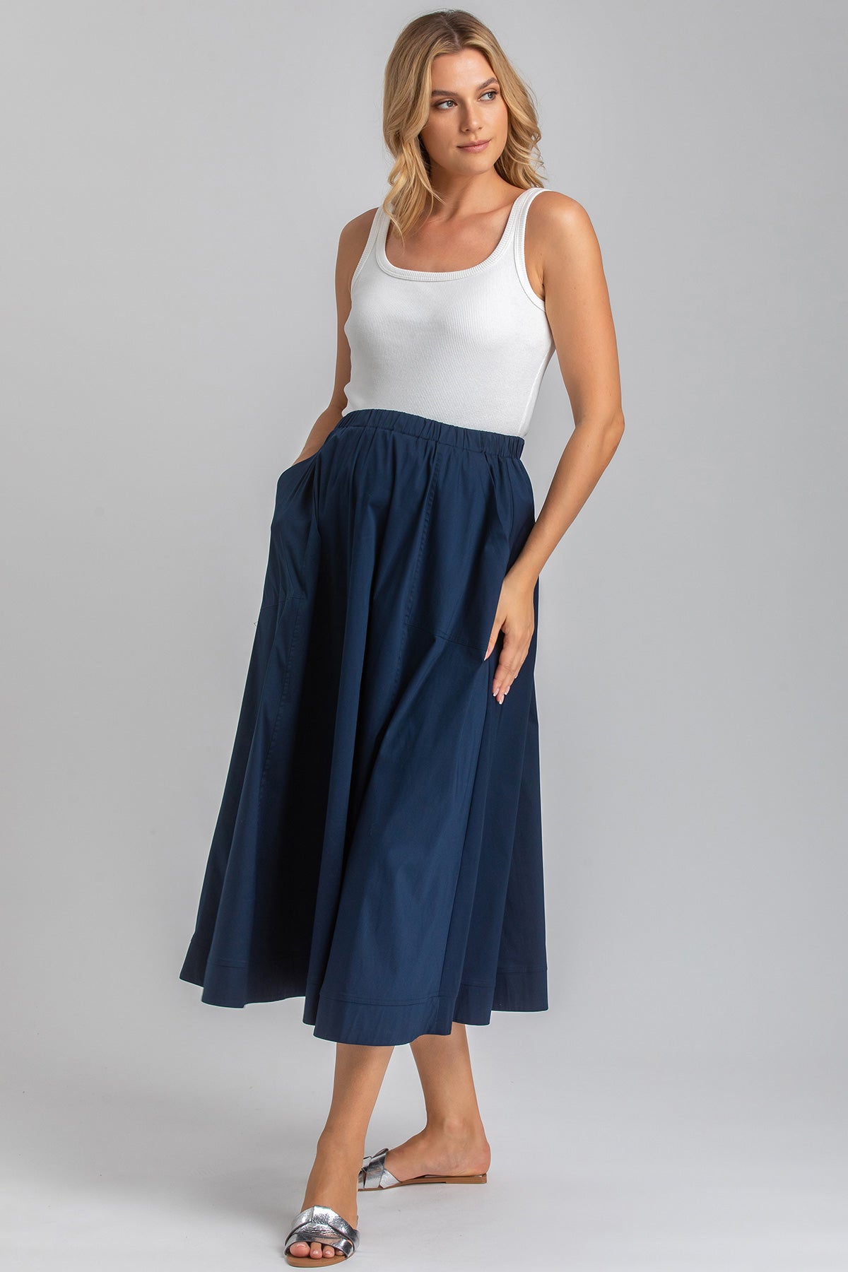 Donna con gonna lunga blu premaman e canotta bianca, moda abbigliamento premaman elegante