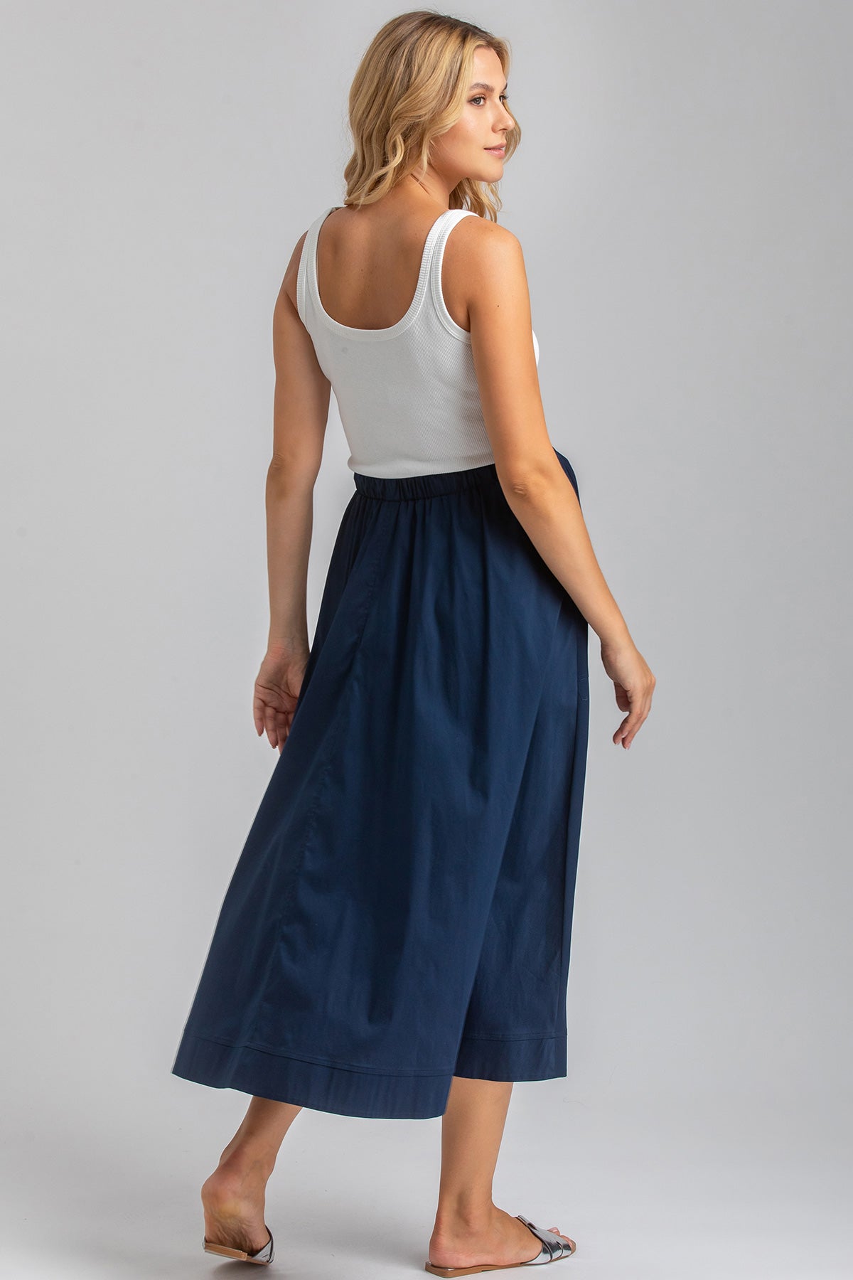 Donna che indossa gonna premaman blu e top bianco, abbigliamento premaman elegante.