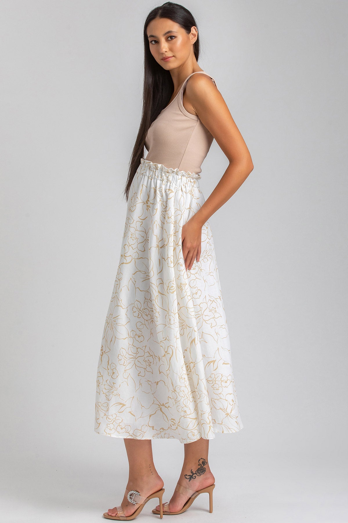 Donna con gonna lunga premaman bianca a fantasia floreale dorata e top beige