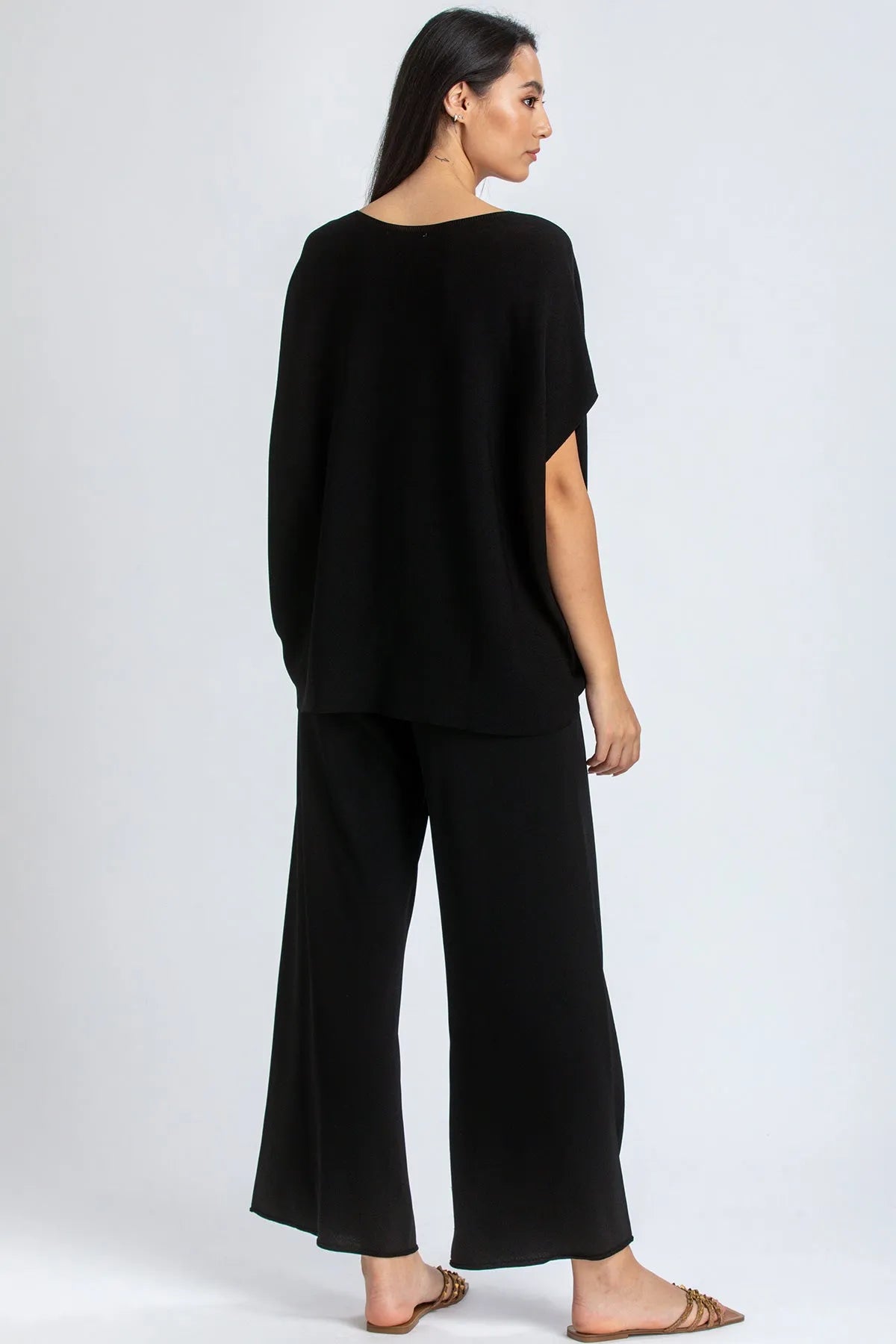 Donna indossa completo premaman nero elegante con pantaloni ampi e maglia a maniche corte.