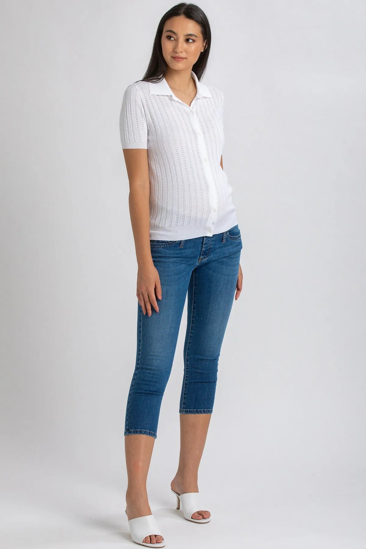 Donna incinta con camicia bianca e jeans premaman skinny blu Capri, sandali bianchi
