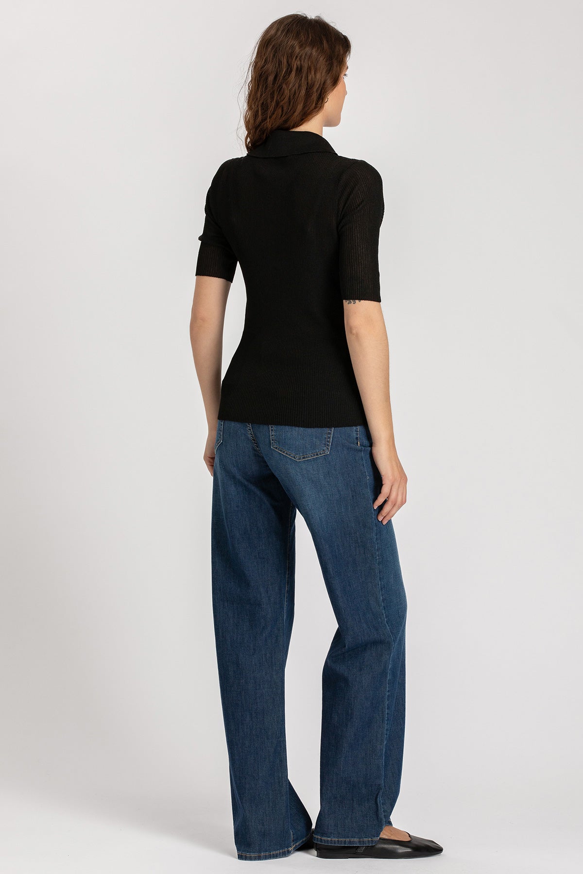 Donna di spalle con maglia nera premaman a maniche corte e jeans premaman ampi