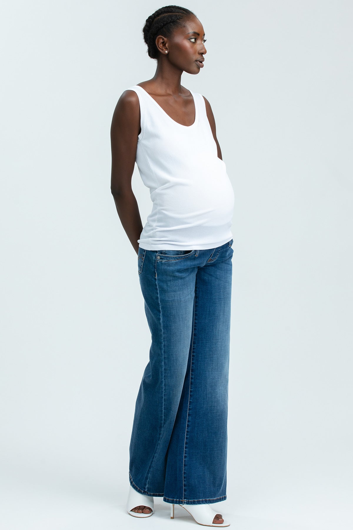 Donna incinta con top bianco e jeans premaman larghi, abbigliamento premaman elegante