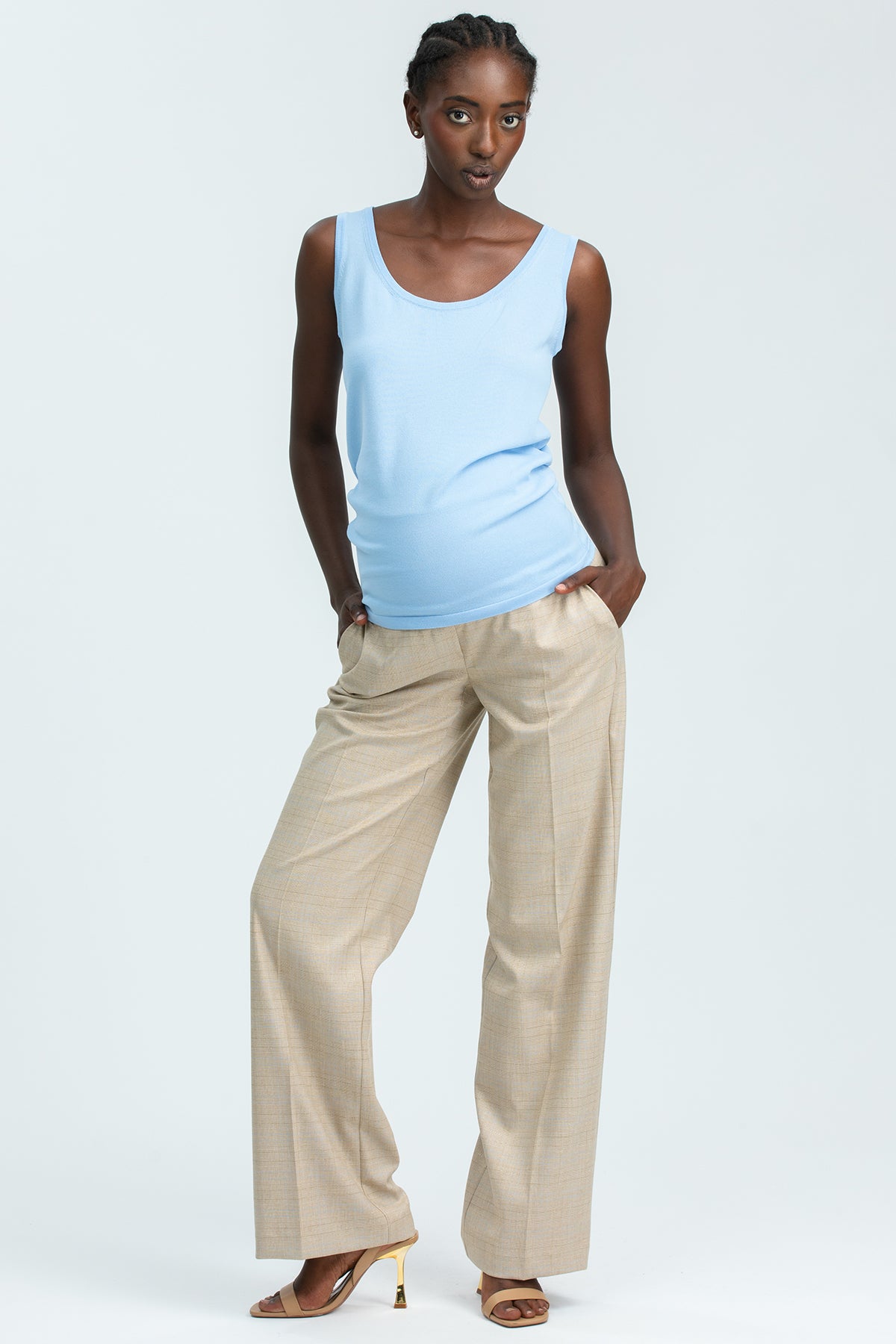 Modella indossa pantaloni premaman beige e top celeste, abbigliamento premaman elegante.