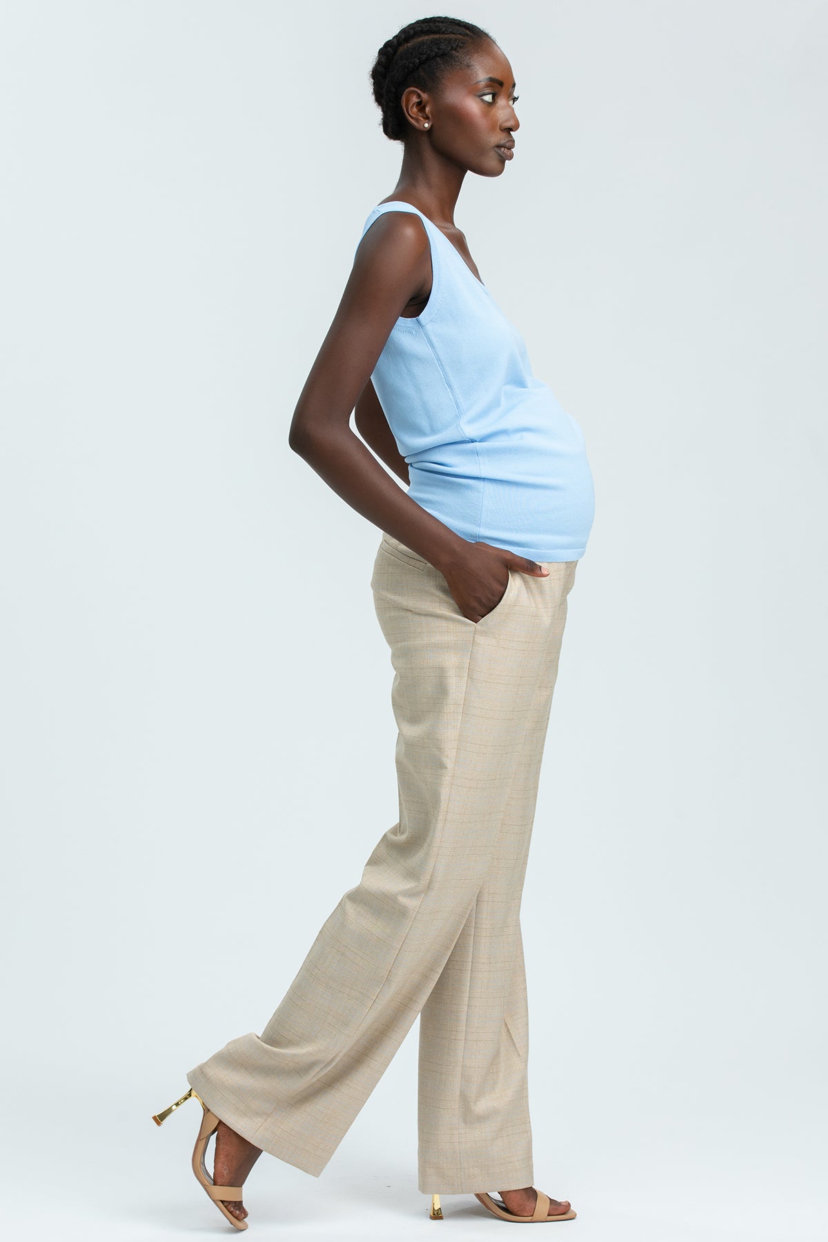 Modella indossa pantaloni premaman beige eleganti e top azzurro, abbigliamento premaman moderno.