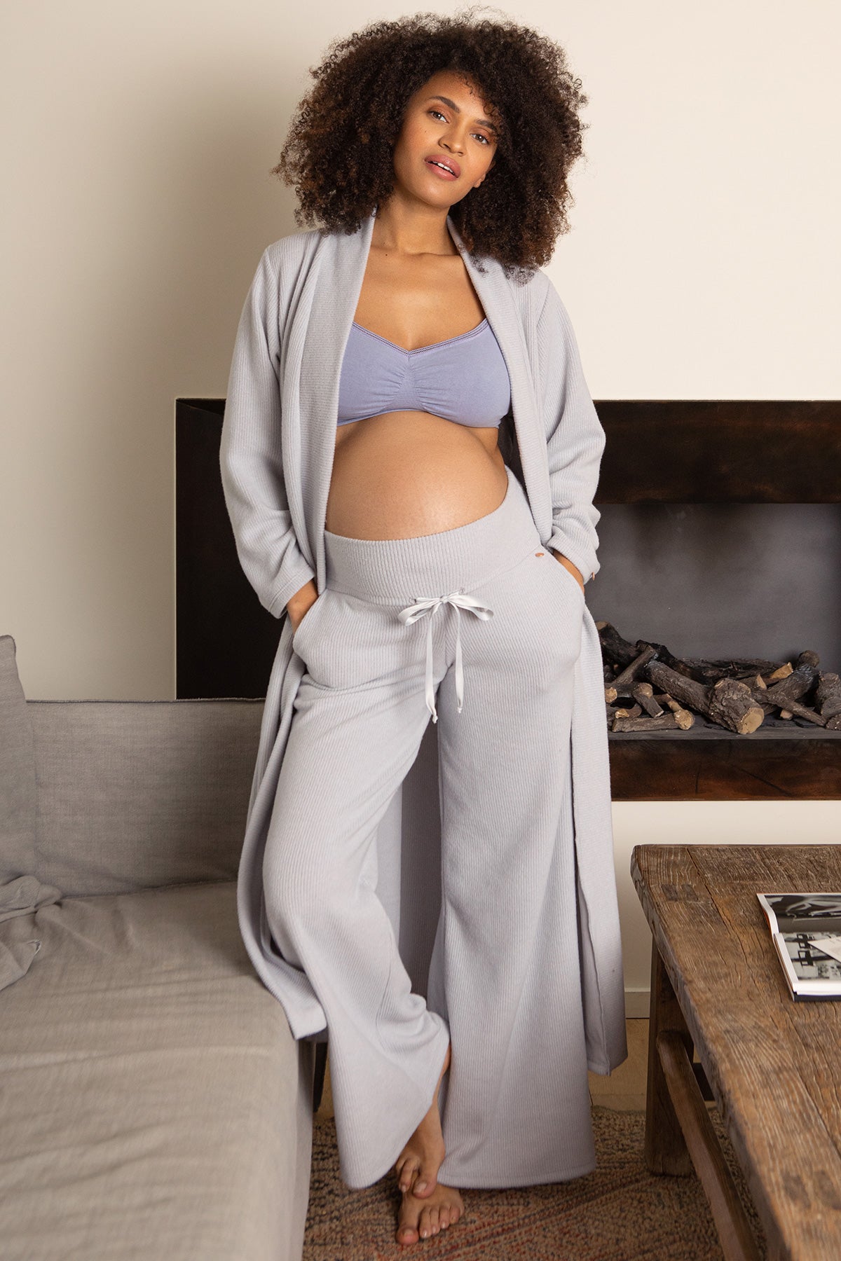 Donna incinta con pantaloni e cardigan premaman in maglia chiara, abbigliamento premaman elegante.