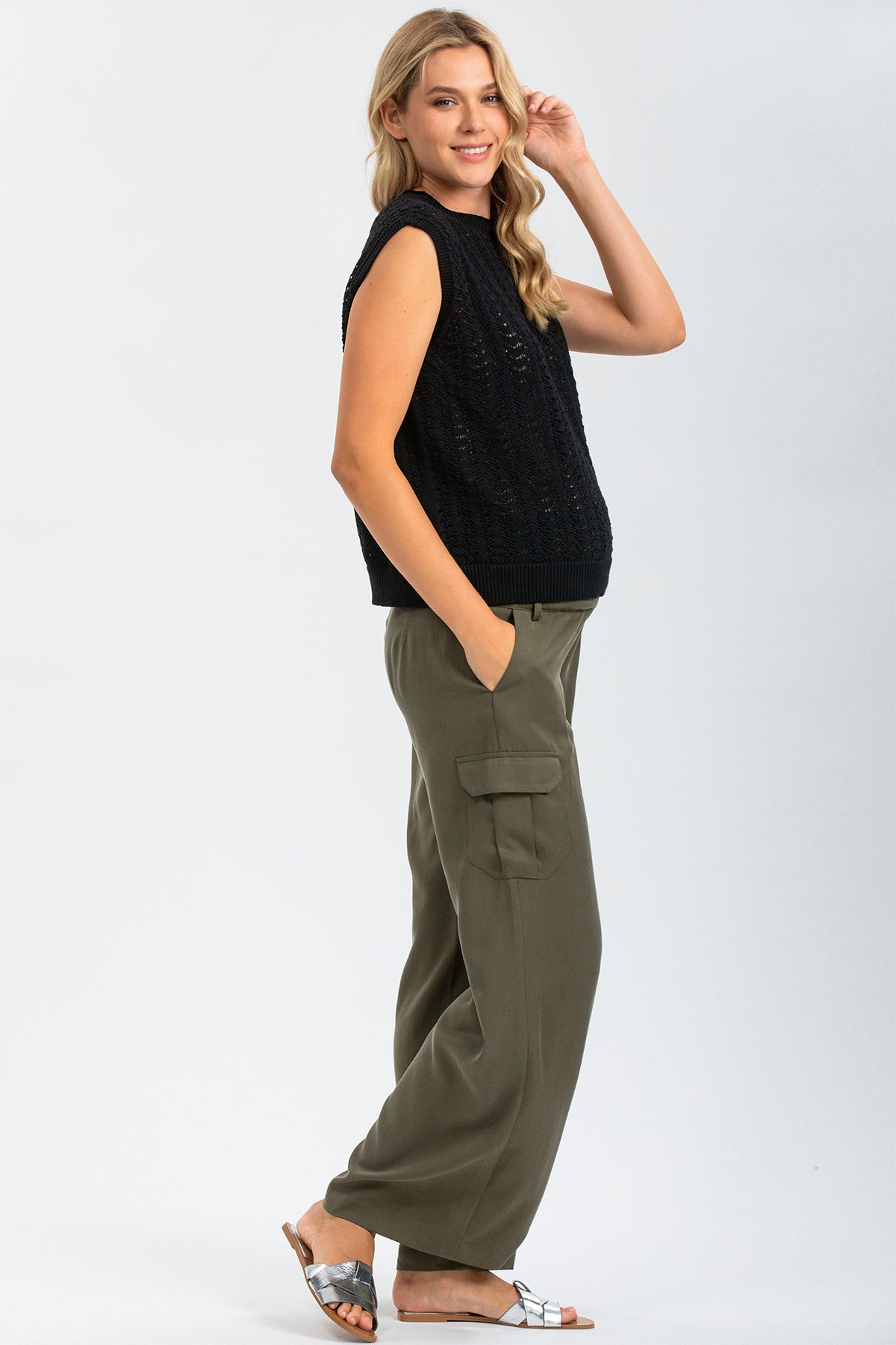 Donna incinta con maglia smanicata nera e pantaloni cargo premaman verdi, look casual