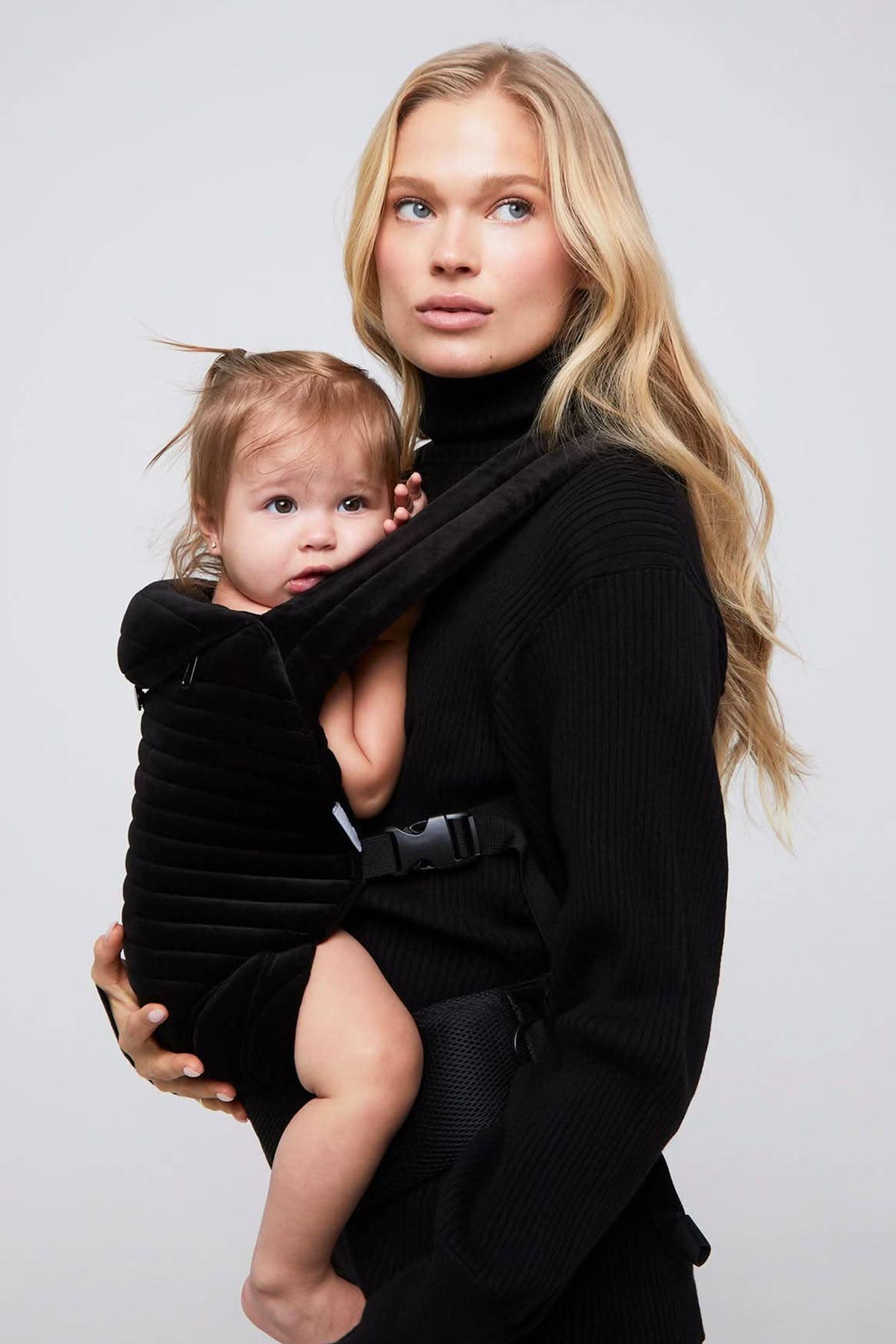 Donna con abbigliamento premaman nero e marsupio porta bebè, look moderno ed elegante.
