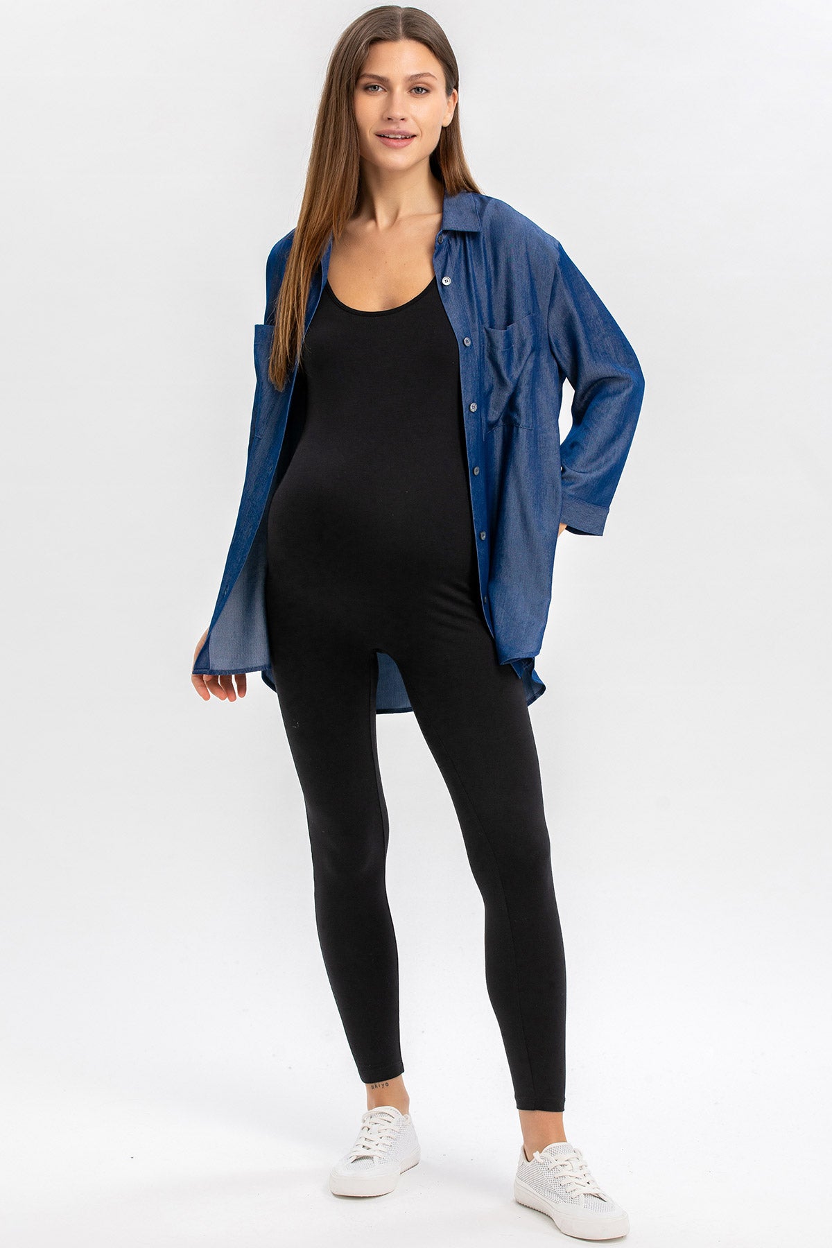 Donna incinta con tuta premaman nera e camicia di jeans, abbigliamento premaman moderno